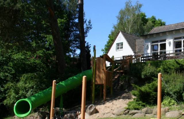 Spielplatz mit Klettermöglichkeit, grüner langer Rutsche und Balance