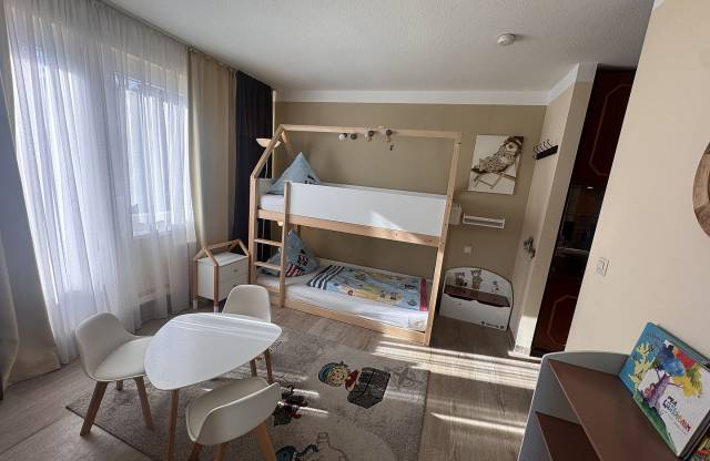 Kinderzimmer mit Doppelbett, Tisch und schönem Teppich