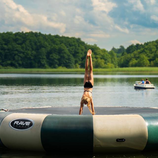 Ein Mädchen macht auf einem runden Wassertrampolin einen Handstand