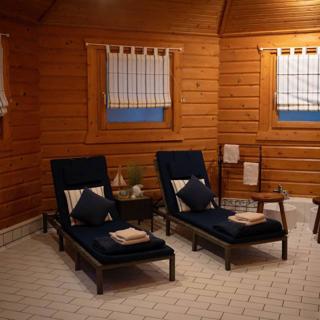 Zwei Liegen mit Handtüchern, Kissen und einem Laufrad in der Holzhütte der Sauna