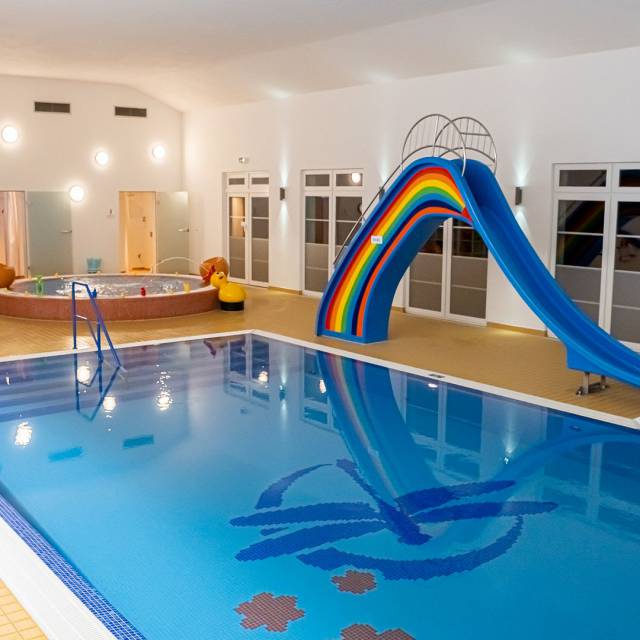 Schwimmbad, mit großer, bunter Rutsche und Babybecken im Hintergrund