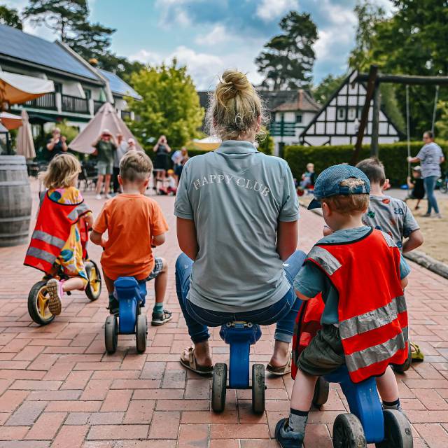 Kinderbetreuerin macht mit Kindern ein Rennen auf dem Laufrad