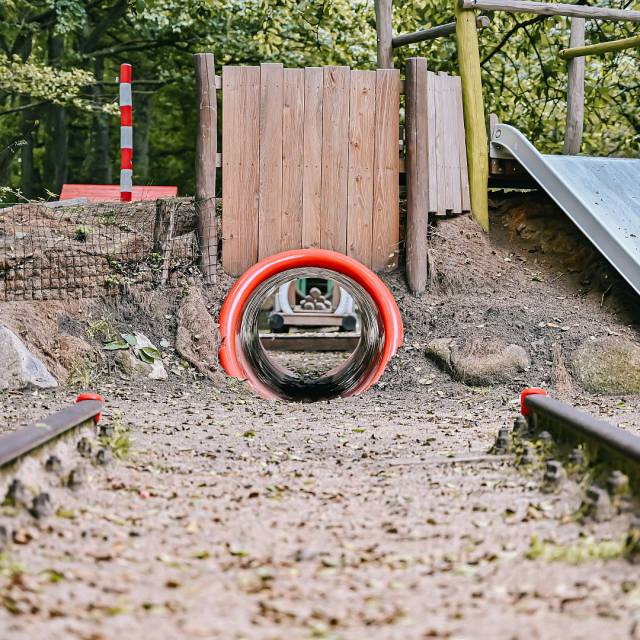 roter Tunnel über den man zu einer Rutsche laufen kann