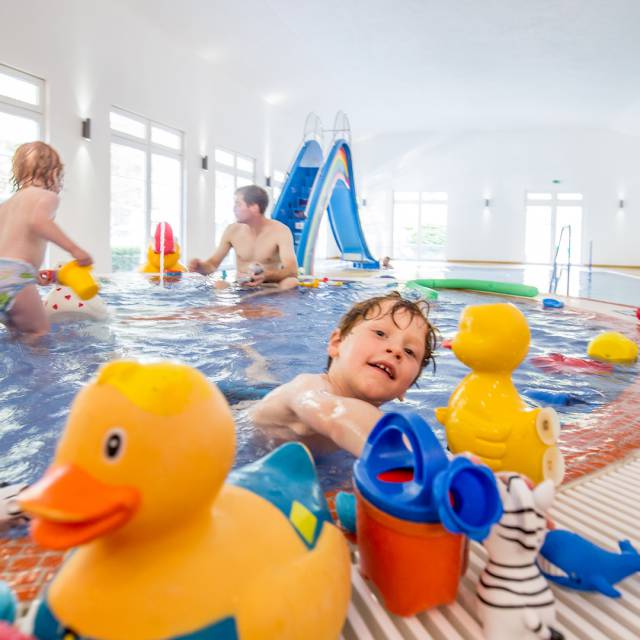 Kinder spielen im Kinderpool mit Gummienten und Spielsachen