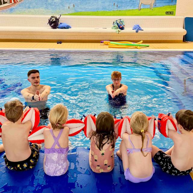Gruppe an Kinder beim Schwimmkurs im Hallenbad des Familienhotels.