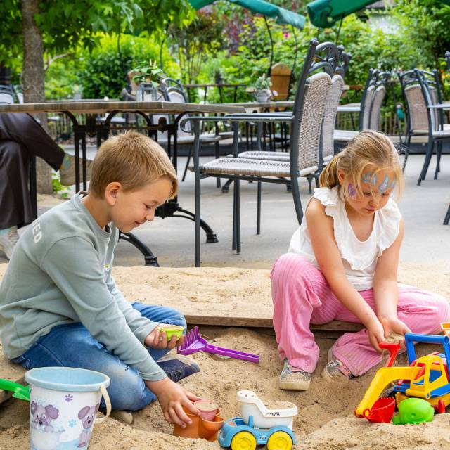 Kinder beim Spielen im Sand im Familotel Rookhus, während Mutter entspannt