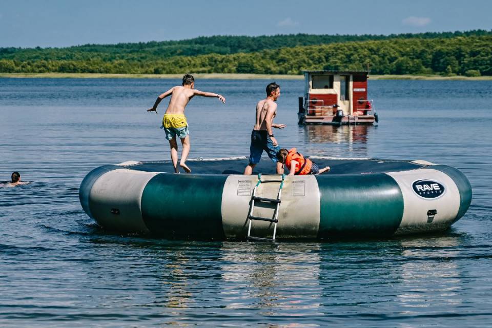 Vater mit Kindern springt auf Wassertrampolin