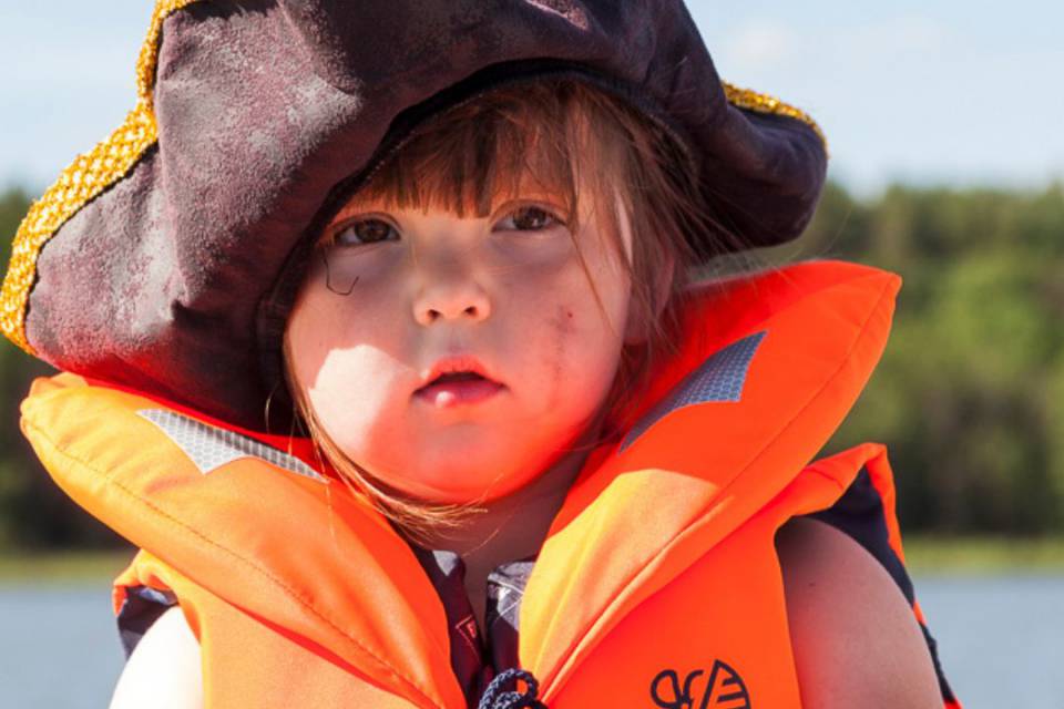 Kleiner Junge mit Piratenhut und Schwimmweste hält ein Steuer in der Hand