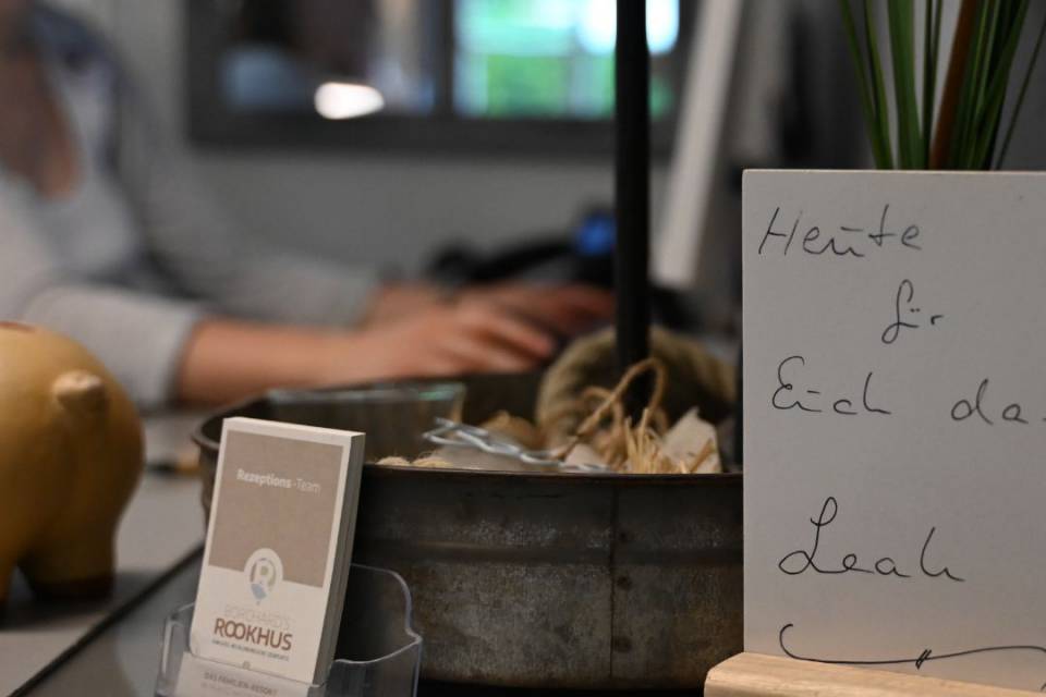 Rezeption mit Flyern und Schild, im Hintergrund eine Rezeptionistin