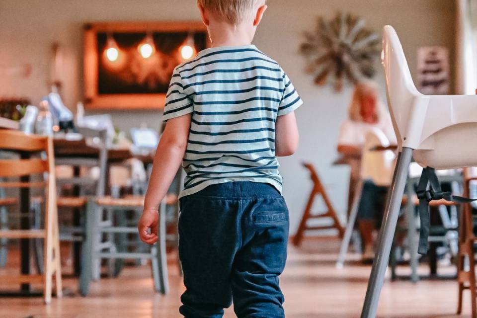 Kleiner Junge in Gummistiefel spaziert durch gemütliches Restaurant im Borchards Rookhus