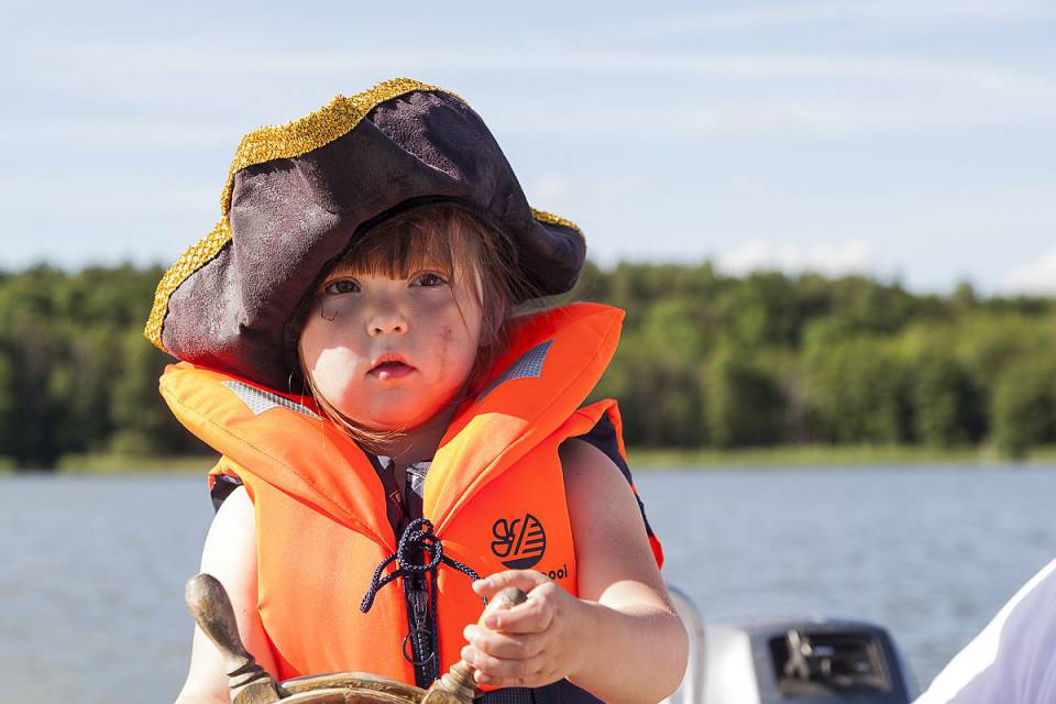 Kleiner Junge mit Schwimmweste, Piratenhut und Steuer in den Händen auf dem Labussee