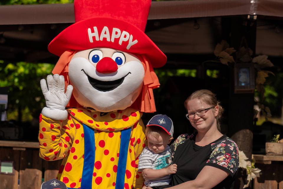 Familie posiert mit dem Familotel Maskottchen Happy