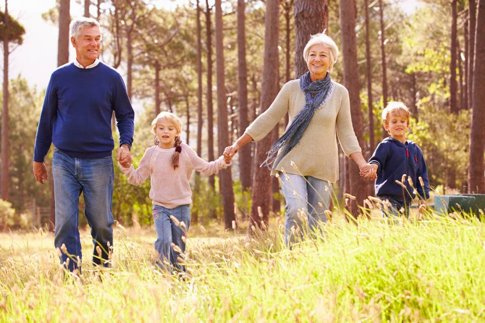 Großeltern laufen mit Enkelkindern durch den Wald