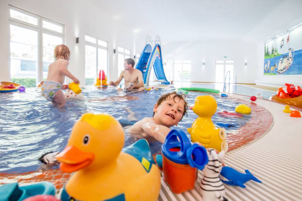 Kinder spielen im Kinderpool mit Gummienten und Spielsachen
