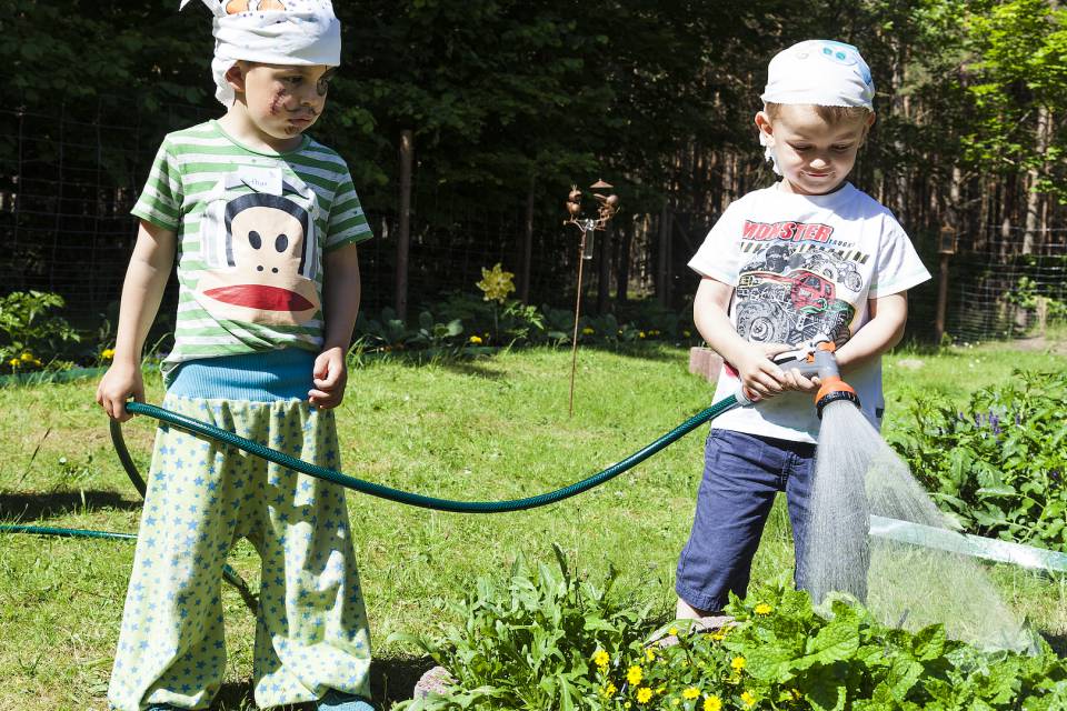 Kinder gießen Kräuterbeete