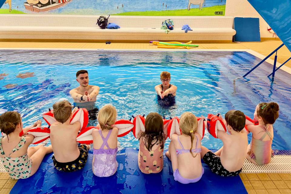 Gruppe an Kinder beim Schwimmkurs im Hallenbad des Familienhotels.