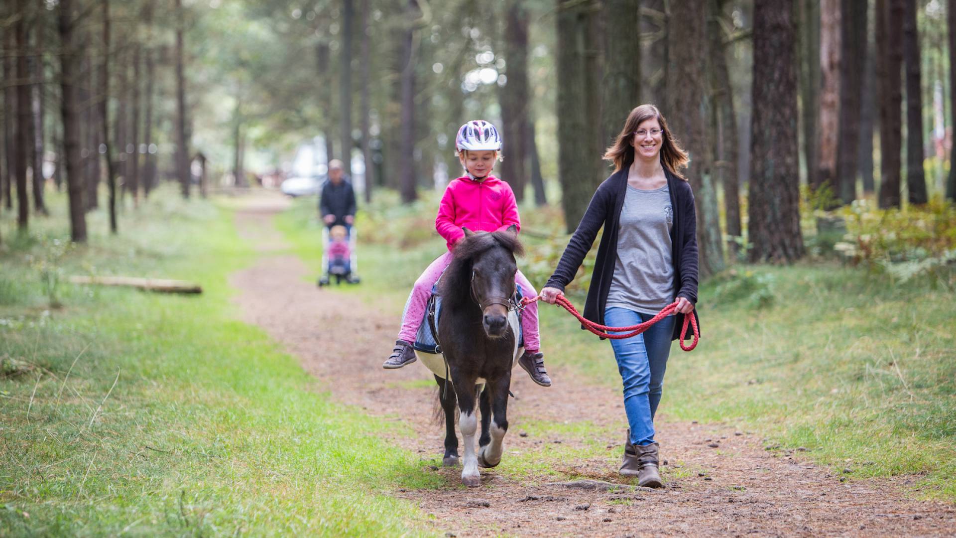 Kind reitet auf einem Pferd durch den Wald