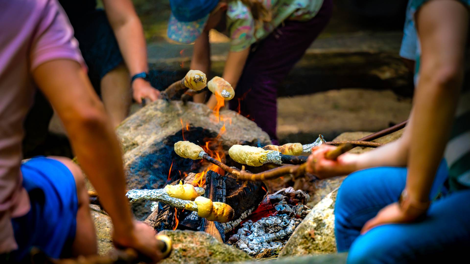 Kinder beim Stockbrot über dem Feuer grillen
