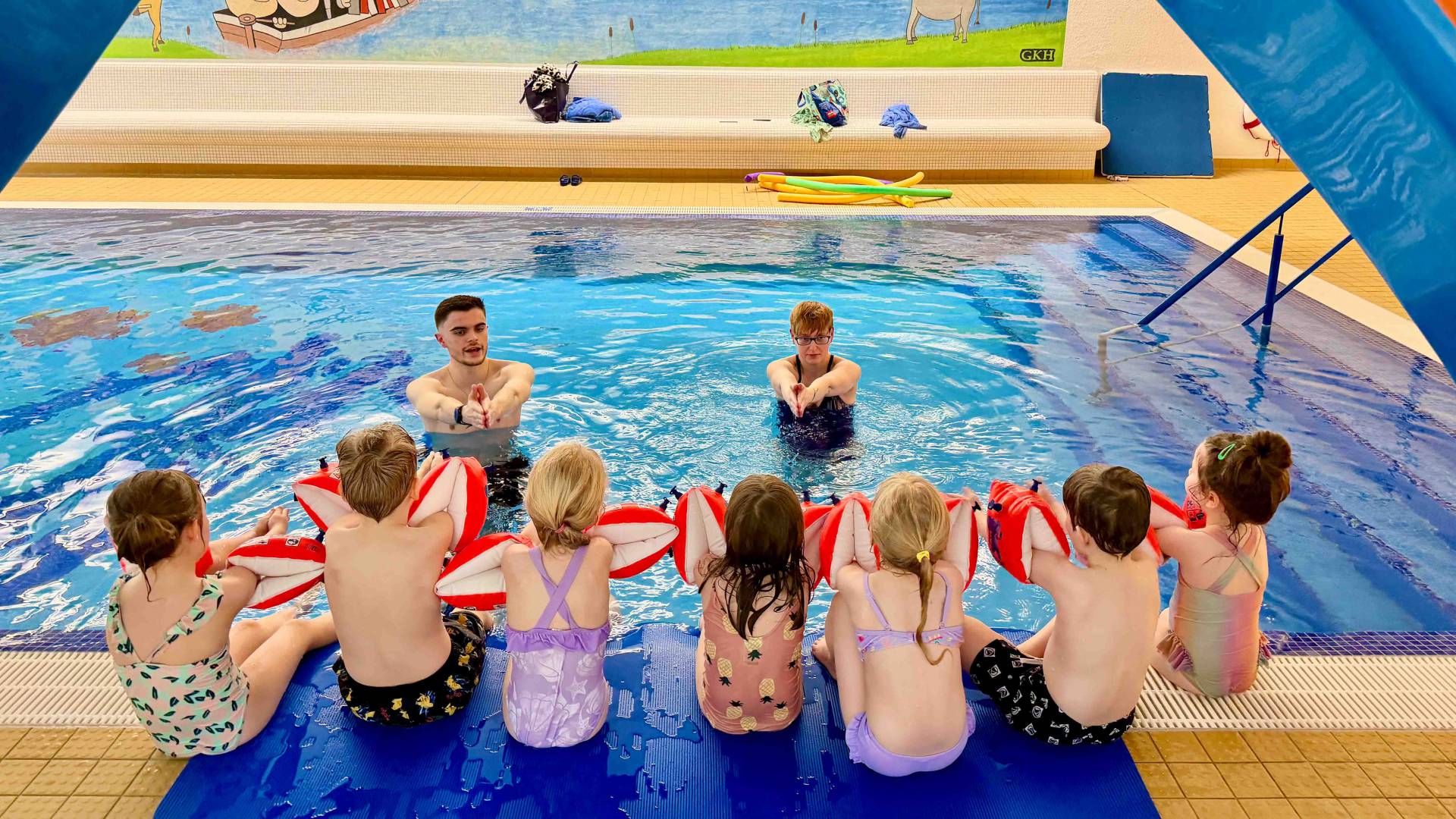 Gruppe an Kinder beim Schwimmkurs im Hallenbad des Familienhotels.